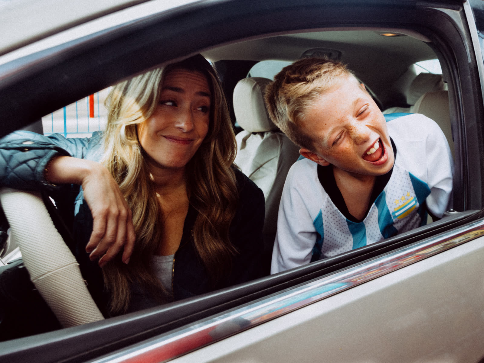 Two kids laughing in the back seat of a car at the drive-thru.
